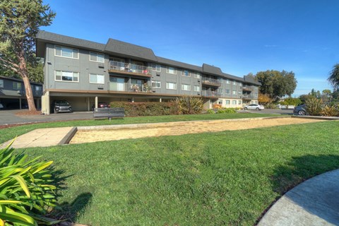 a large apartment building with a grass yard in front of it