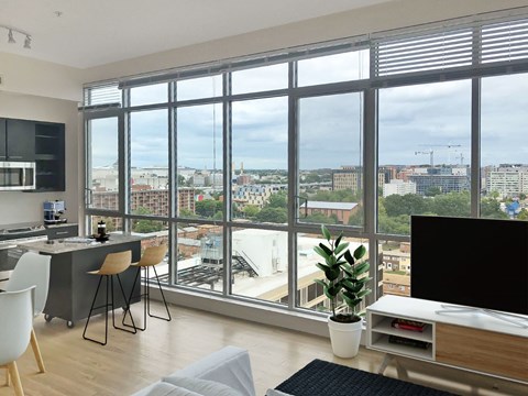 A modern living room with a view of the cityscape outside the large windows.