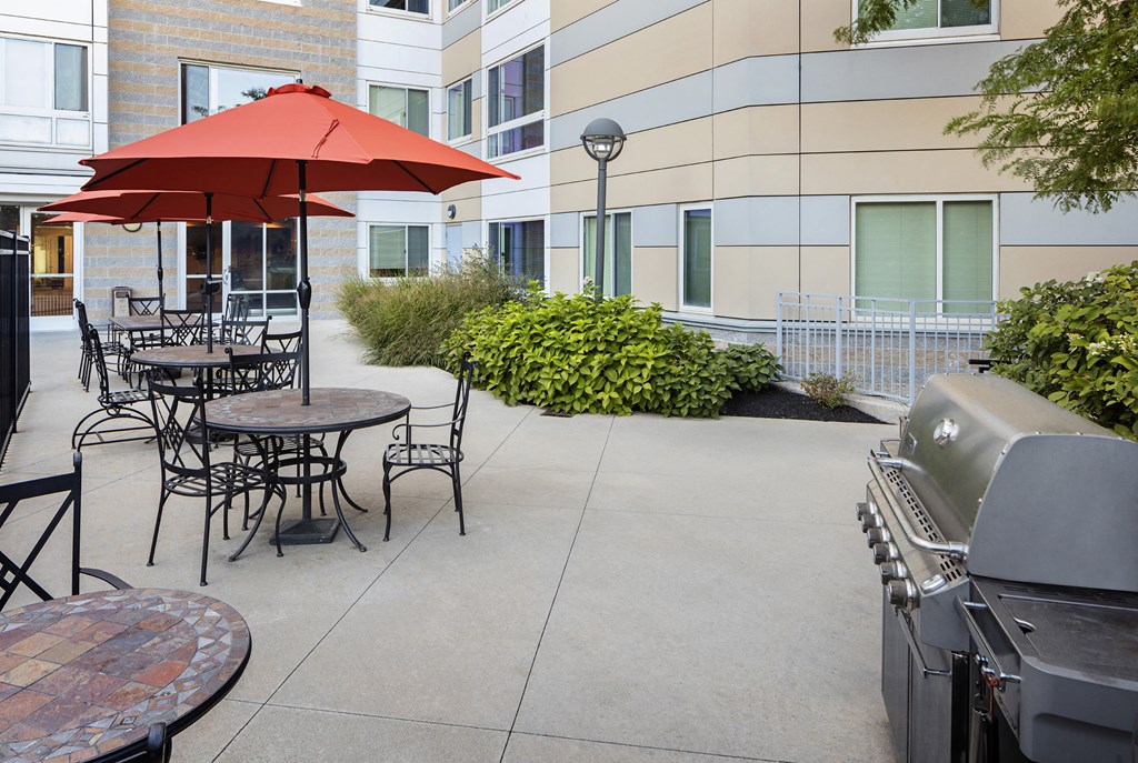 a patio with tables and chairs and umbrellas in front of a building