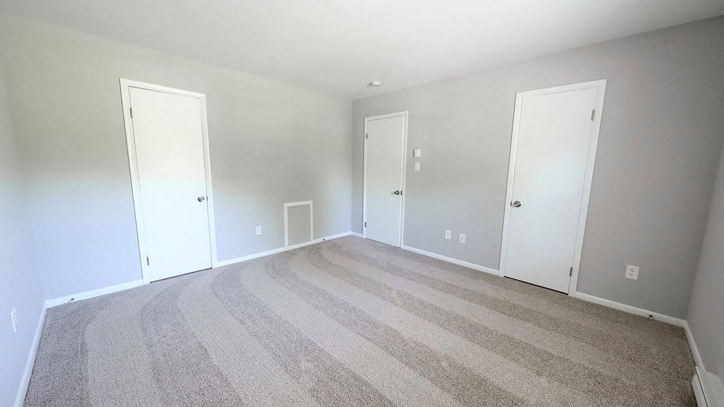 a empty bedroom with two doors and a carpeted floor