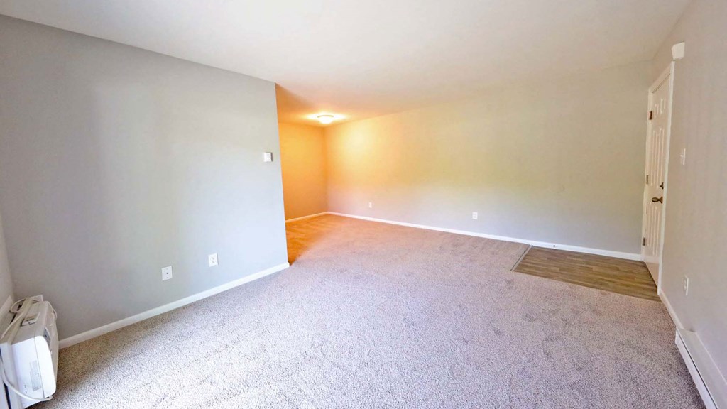a empty living room with carpet and a door to a bedroom