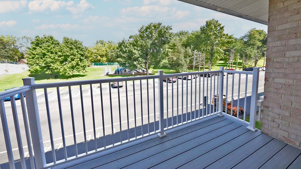 a balcony with a view of a parking lot and trees