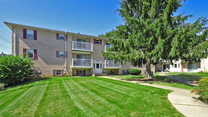 an apartment building with a lawn and a tree in front of it