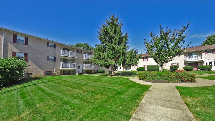 the view of an apartment building with a lawn and sidewalk