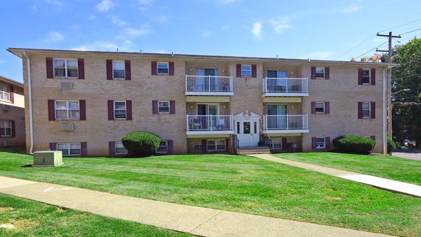 a large brick apartment building with a green lawn