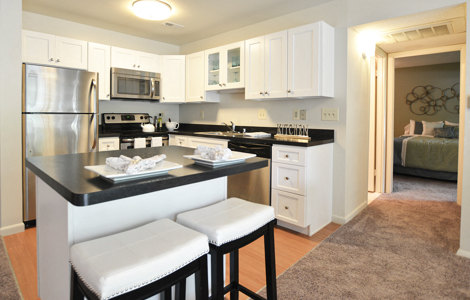 A kitchen with white cabinets and a black countertop.