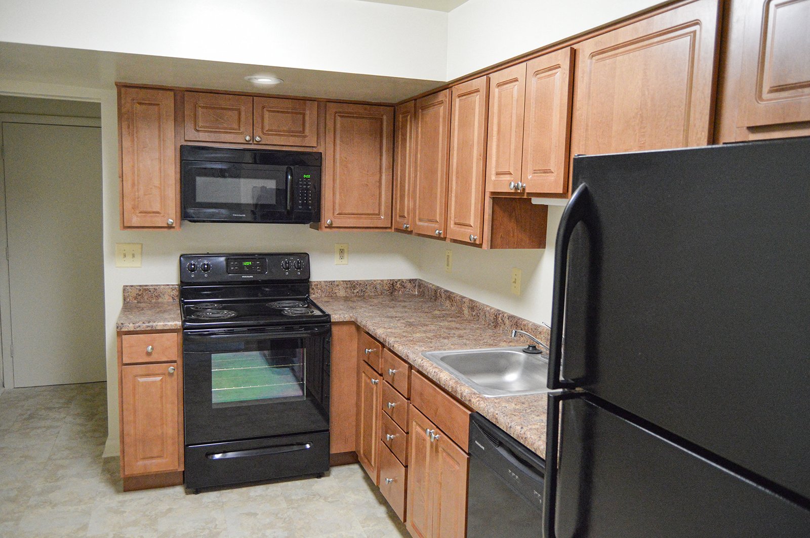 A black refrigerator is on the right side of a kitchen.