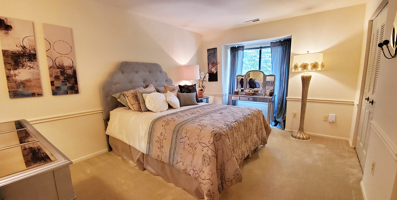 A bedroom with a large bed and a painting on the wall.