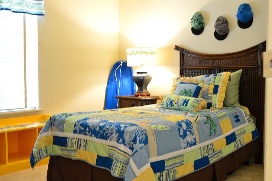 a bedroom with a bed and a blue surfboard in the corner