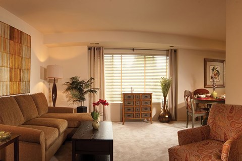A living room with a brown sofa, a wooden cabinet, and a table with a vase of flowers.