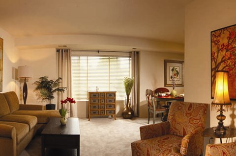 A living room with a couch, chairs, and a table with a vase of flowers on it.