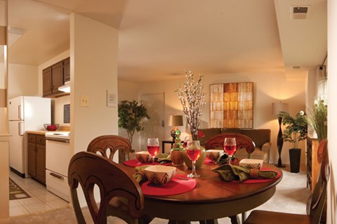 A dining room with a table set for two with wine glasses and plates.