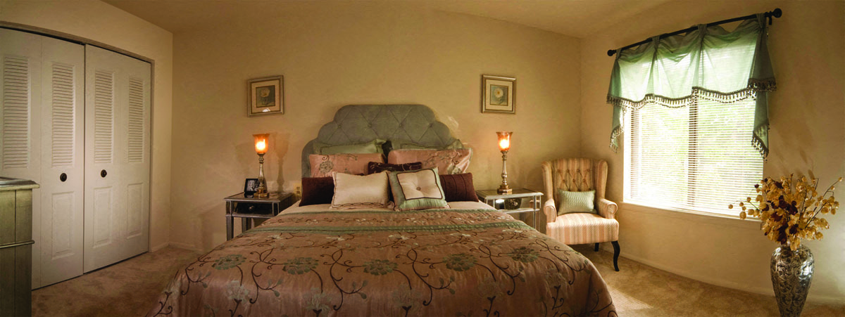 A bedroom with a bed, chair, and two lamps.