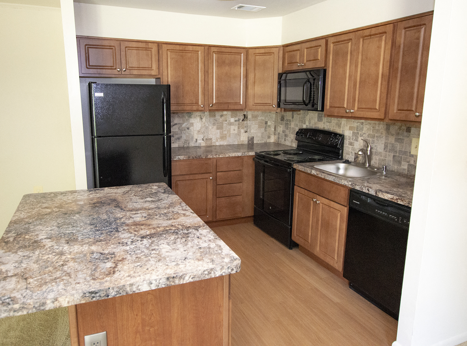 A kitchen with a granite counter top and black appliances.