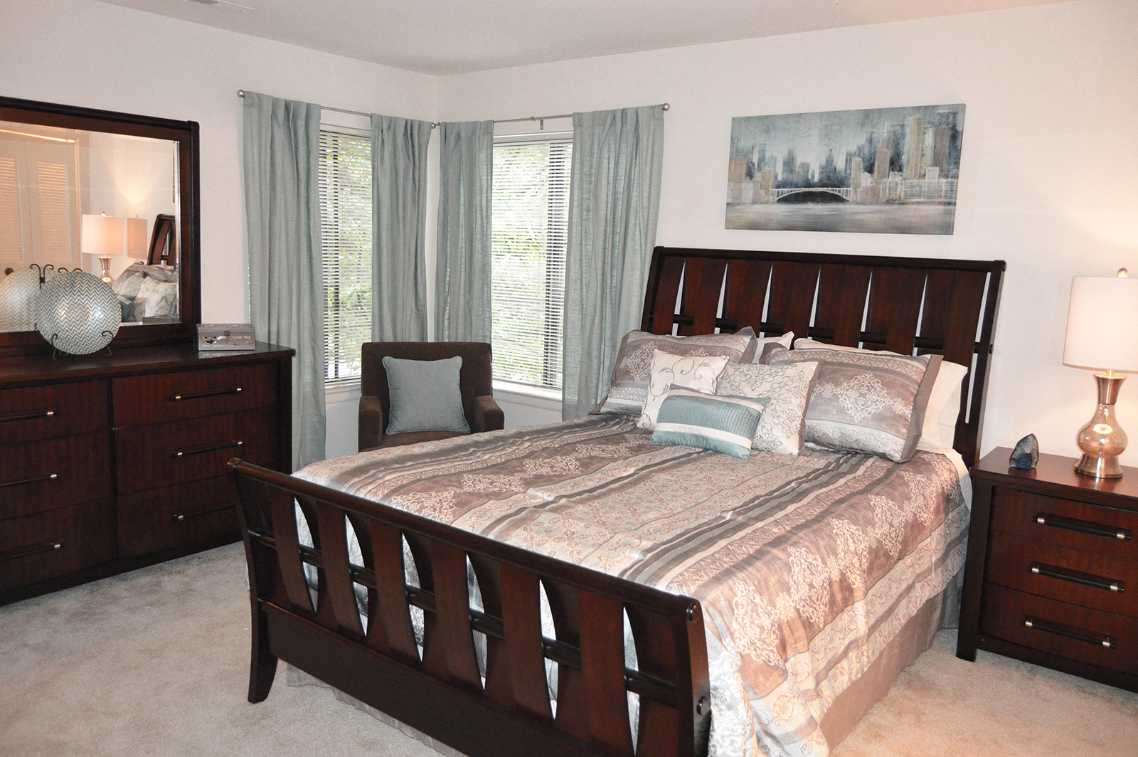 A bedroom with a large bed, a dresser, and a painting on the wall.