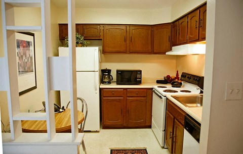 A small kitchen with a white refrigerator and wooden cabinets.
