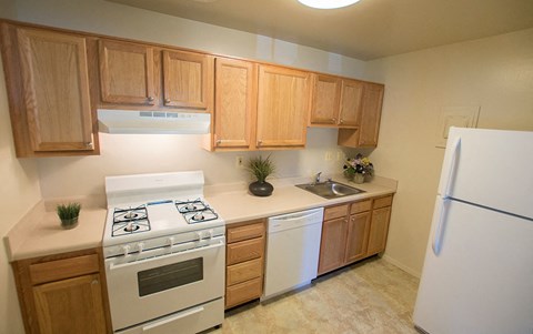 A kitchen with a white stove top oven and wooden cabinets.