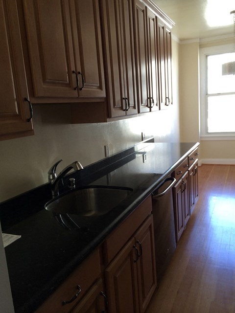 a view of a kitchen with a sink and wooden cabinets