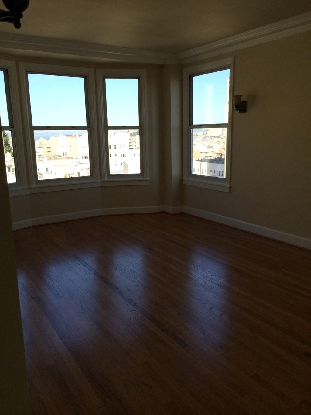 an empty living room with wooden floors and windows