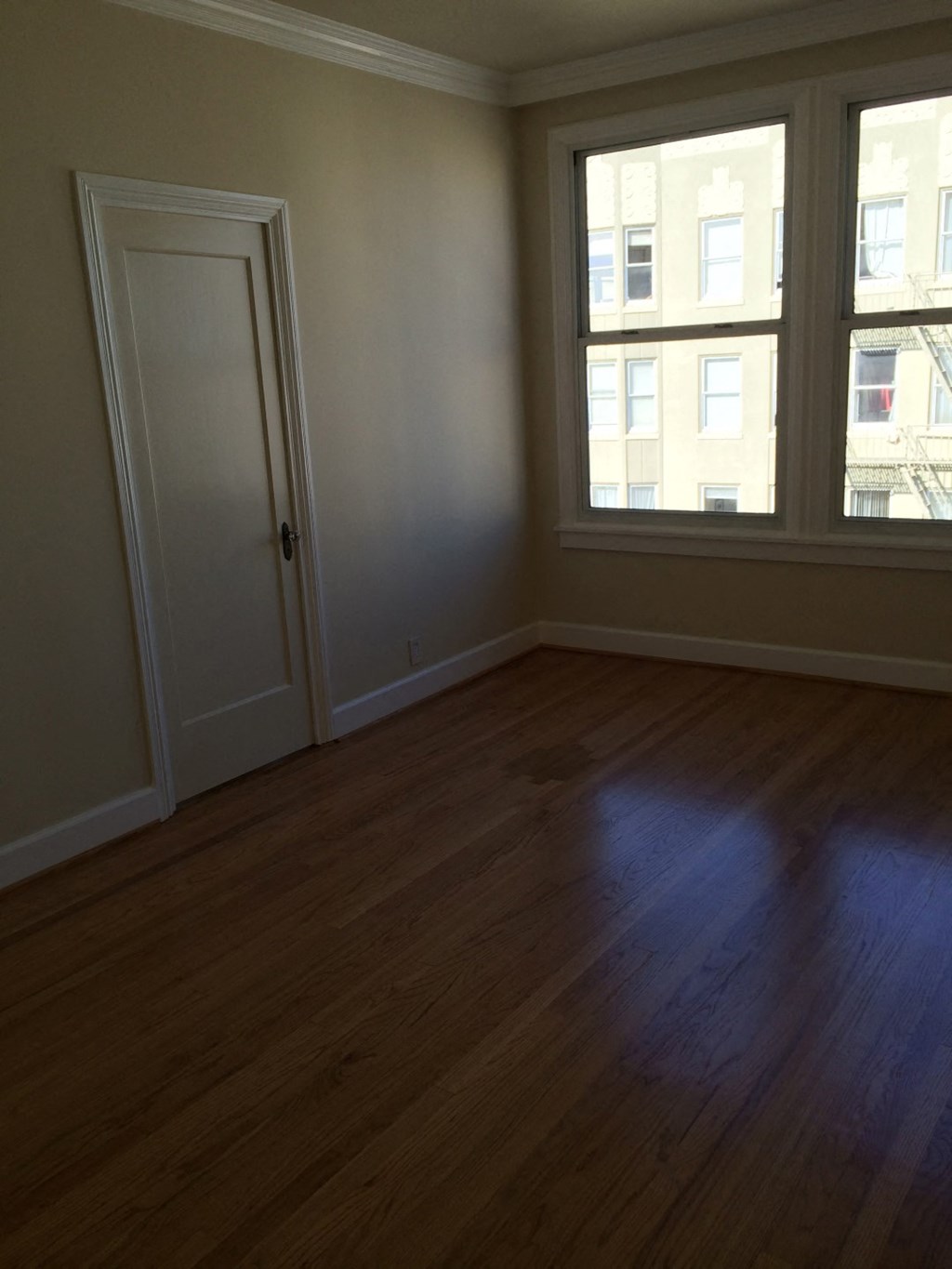 an empty living room with a wooden floor and two windows