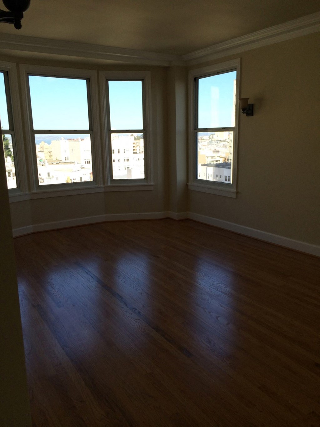 an empty living room with a wooden floor and four windows