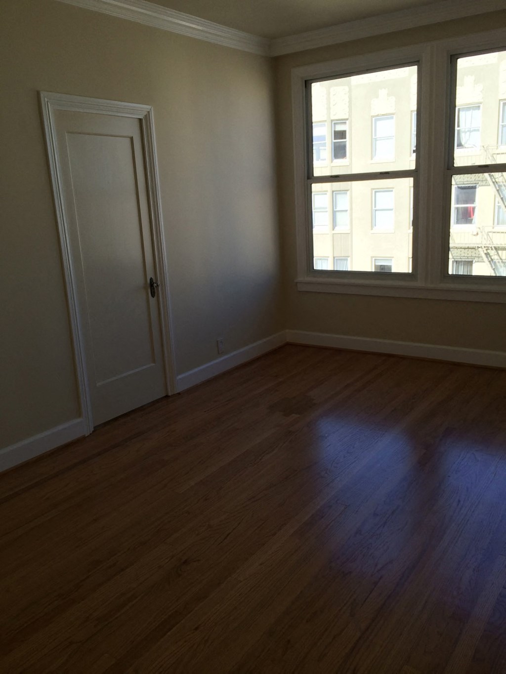 an empty living room with a wooden floor and two windows