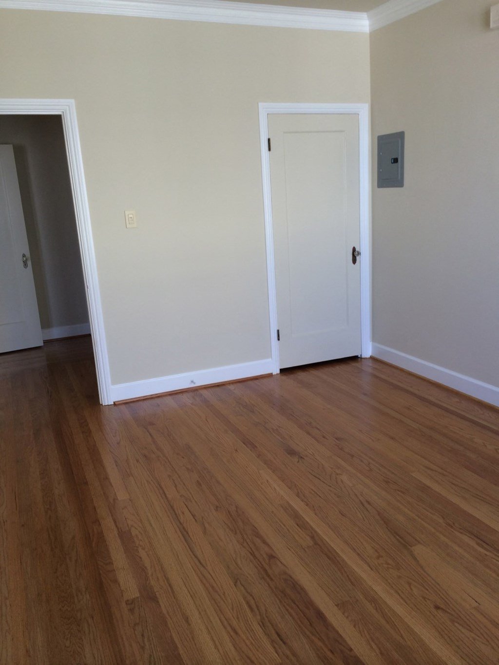 an empty living room with wooden floors and a white door