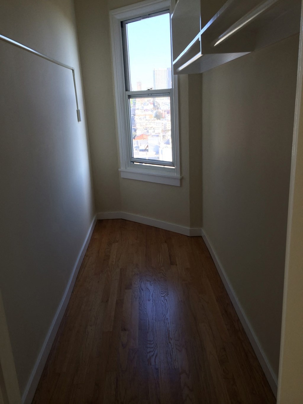 an empty room with a window and wooden floors