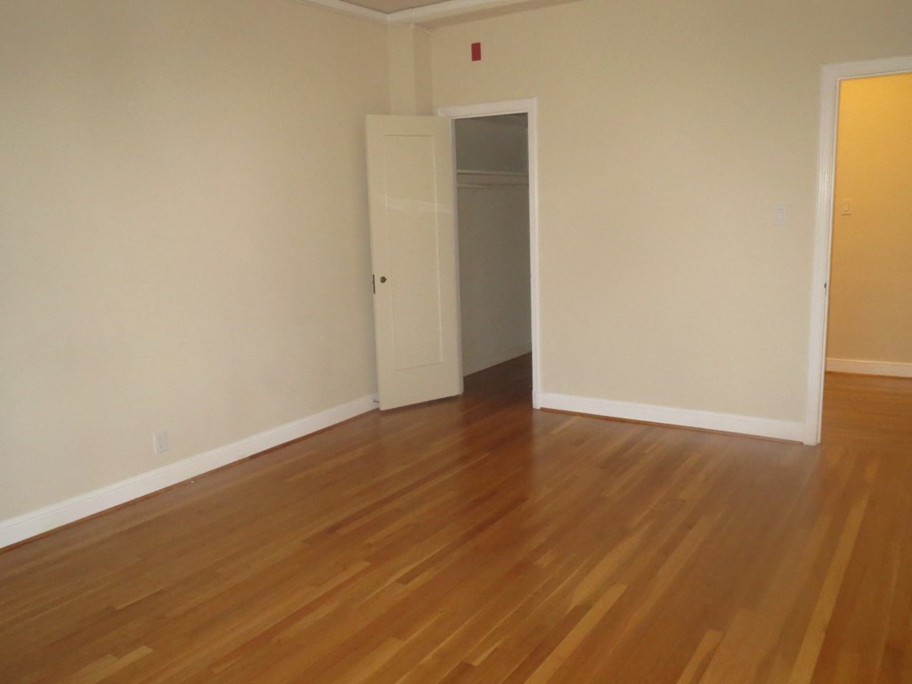 an empty living room with wooden floors and a door to a closet
