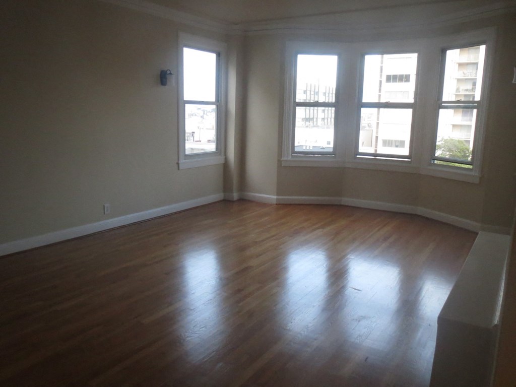 an empty living room with wooden floors and windows