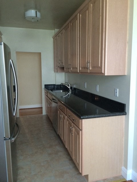 a kitchen with wooden cabinets and a black counter top
