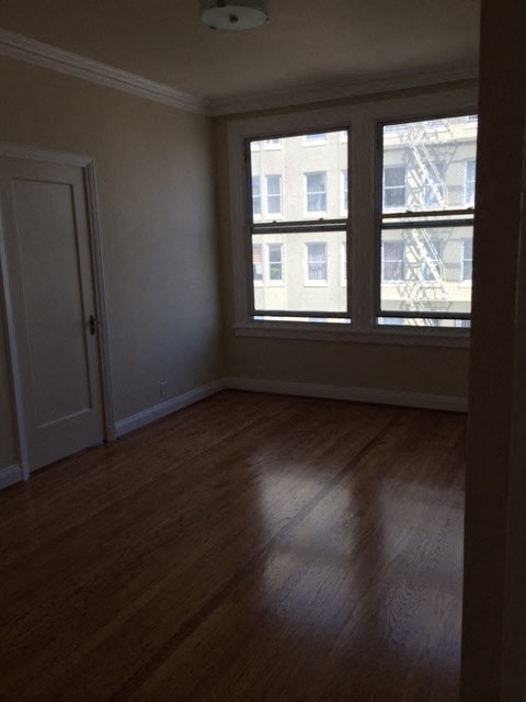 an empty living room with a window and wooden floors