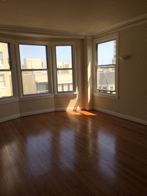 an empty living room with a wood floor and three windows