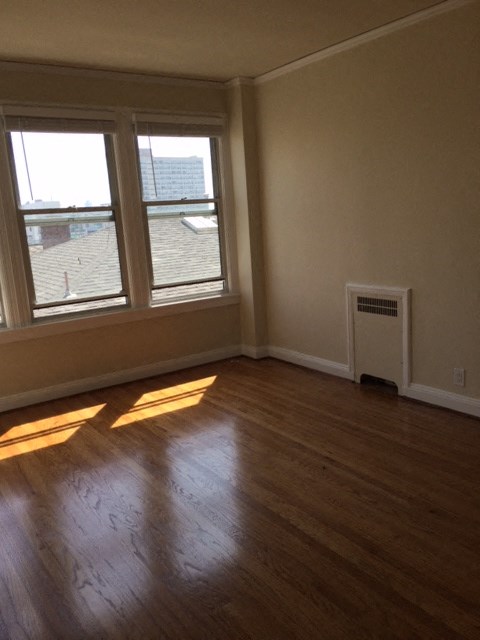 an empty living room with wood floors and three windows