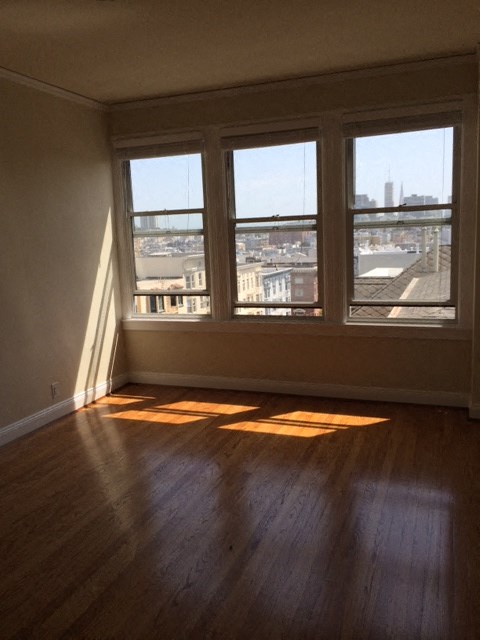 an empty living room with three windows and wood floors
