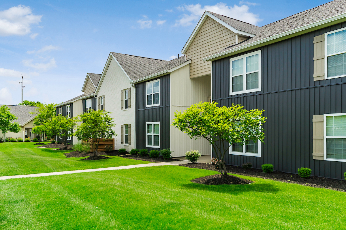 a row of houses with green grass and trees in front of them