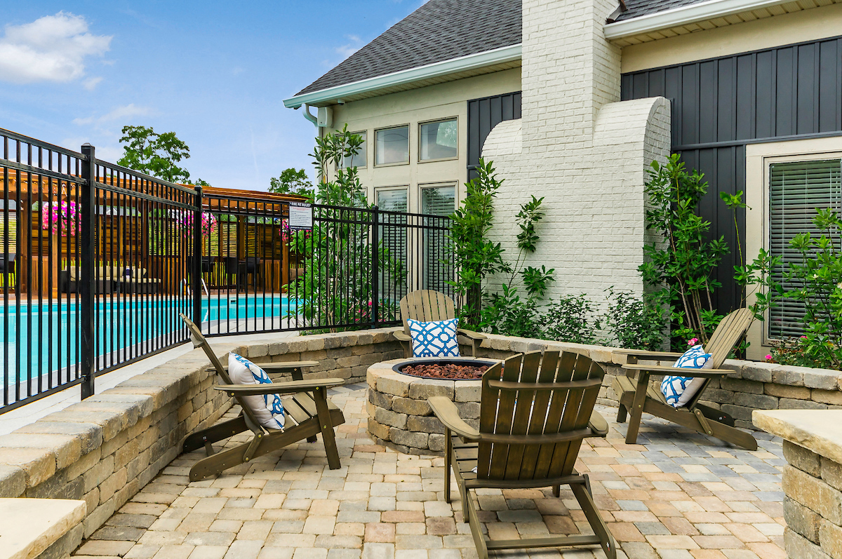 an outdoor patio with chairs and a fire pit in front of a pool