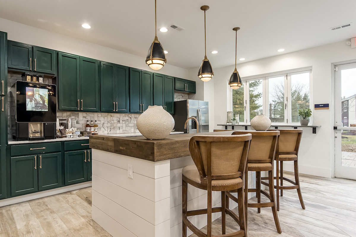 a kitchen with green cabinets and a center island with stools