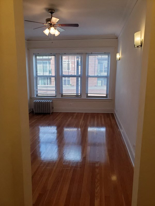 a living room with a wood floor and three windows
