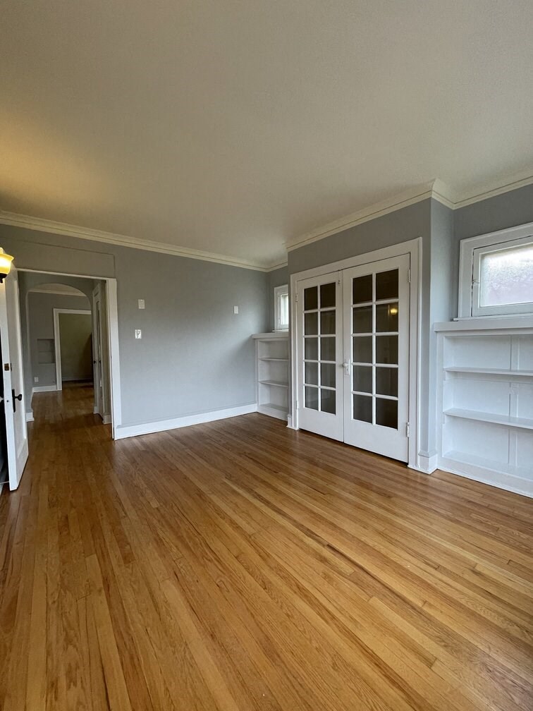 an empty living room with a wooden floor and white doors