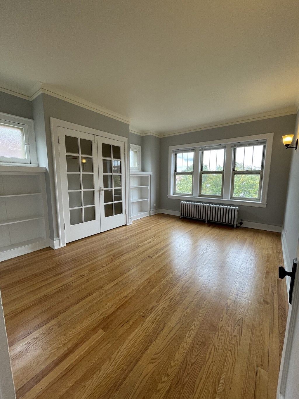 an empty living room with a hard wood floor and white doors