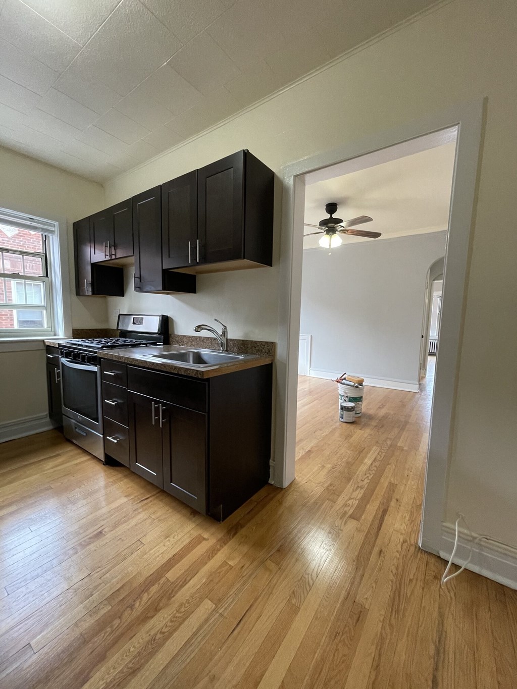 an empty kitchen with black cabinets and a ceiling fan