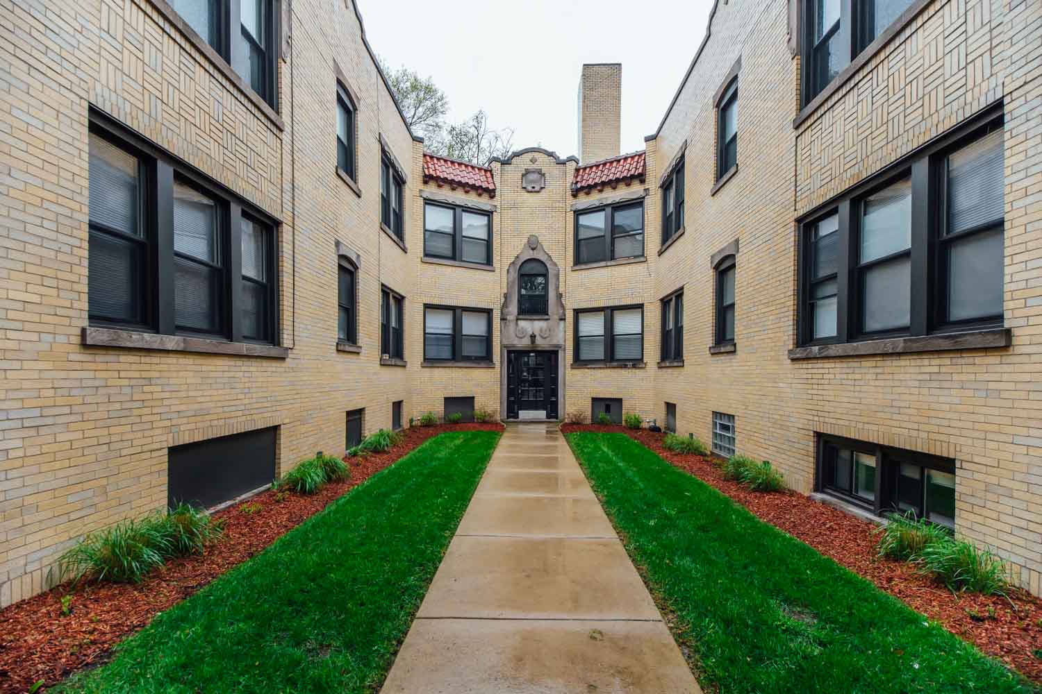 an exterior view of a brick building with a sidewalk and grass