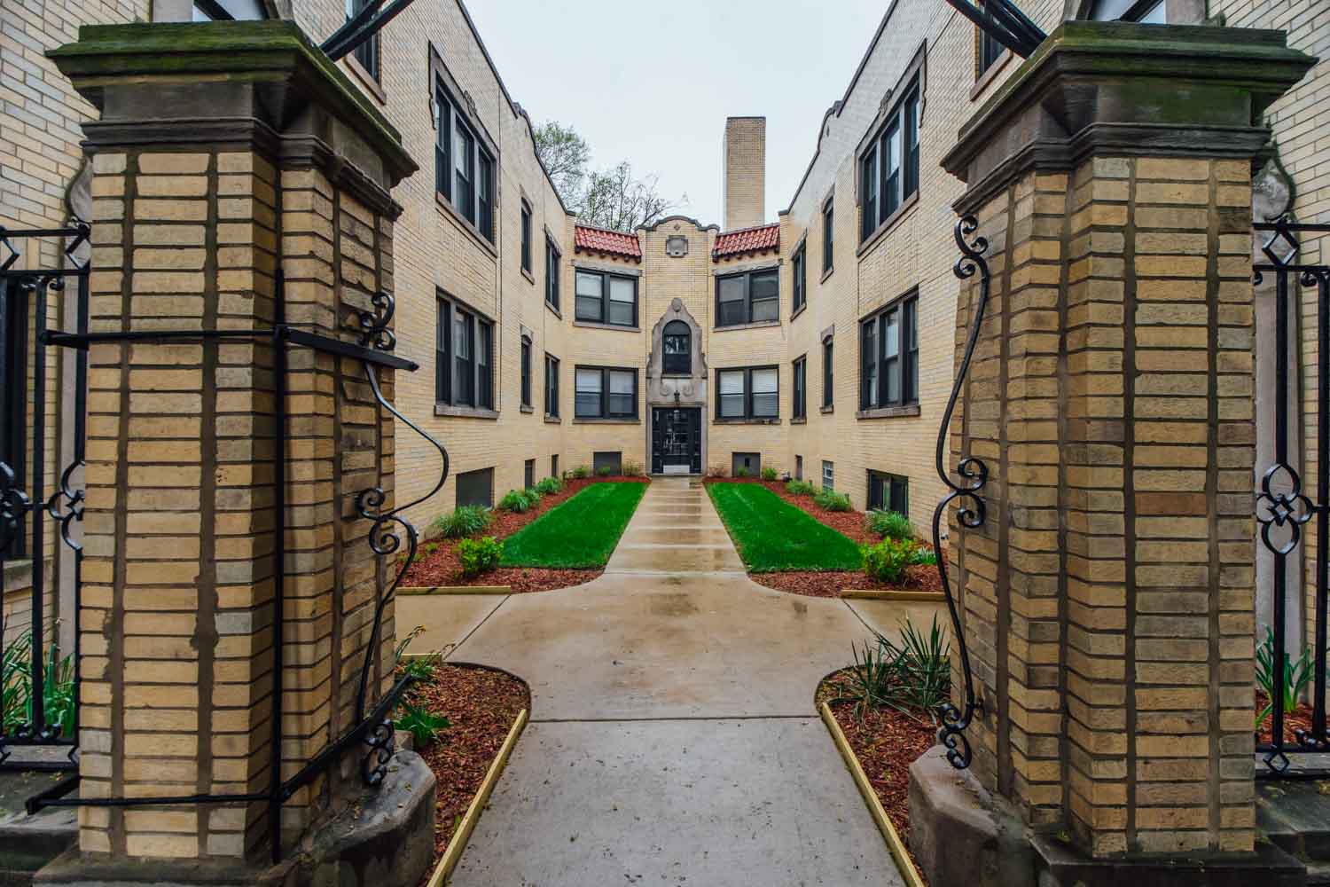 the entrance to a building with a green lawn and walkway