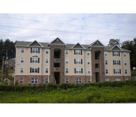 an apartment building with three stories and a field