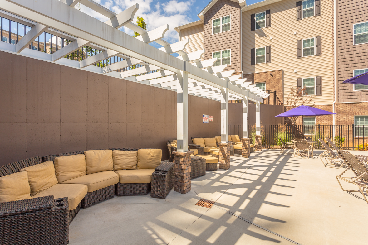 a patio with couches and tables and umbrellas in front of a building