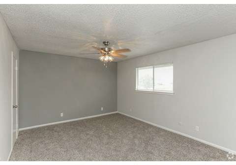 an empty bedroom with a ceiling fan and a window