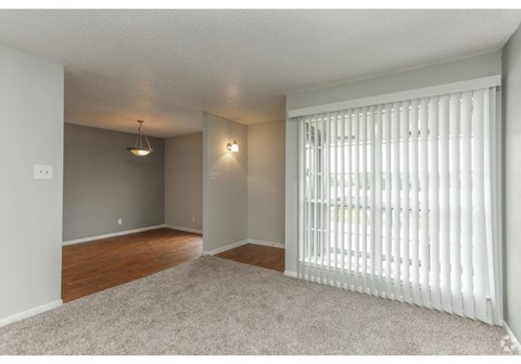 an empty living room with a large window with white blinds