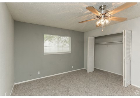an empty bedroom with a ceiling fan and a closet