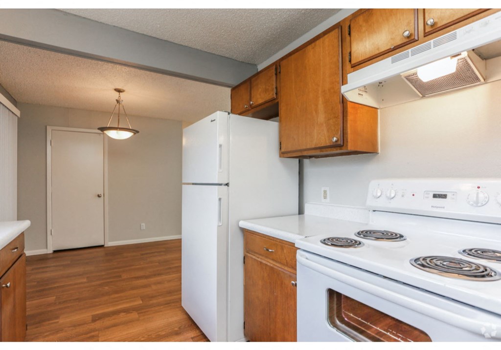 an empty kitchen with a white stove and refrigerator